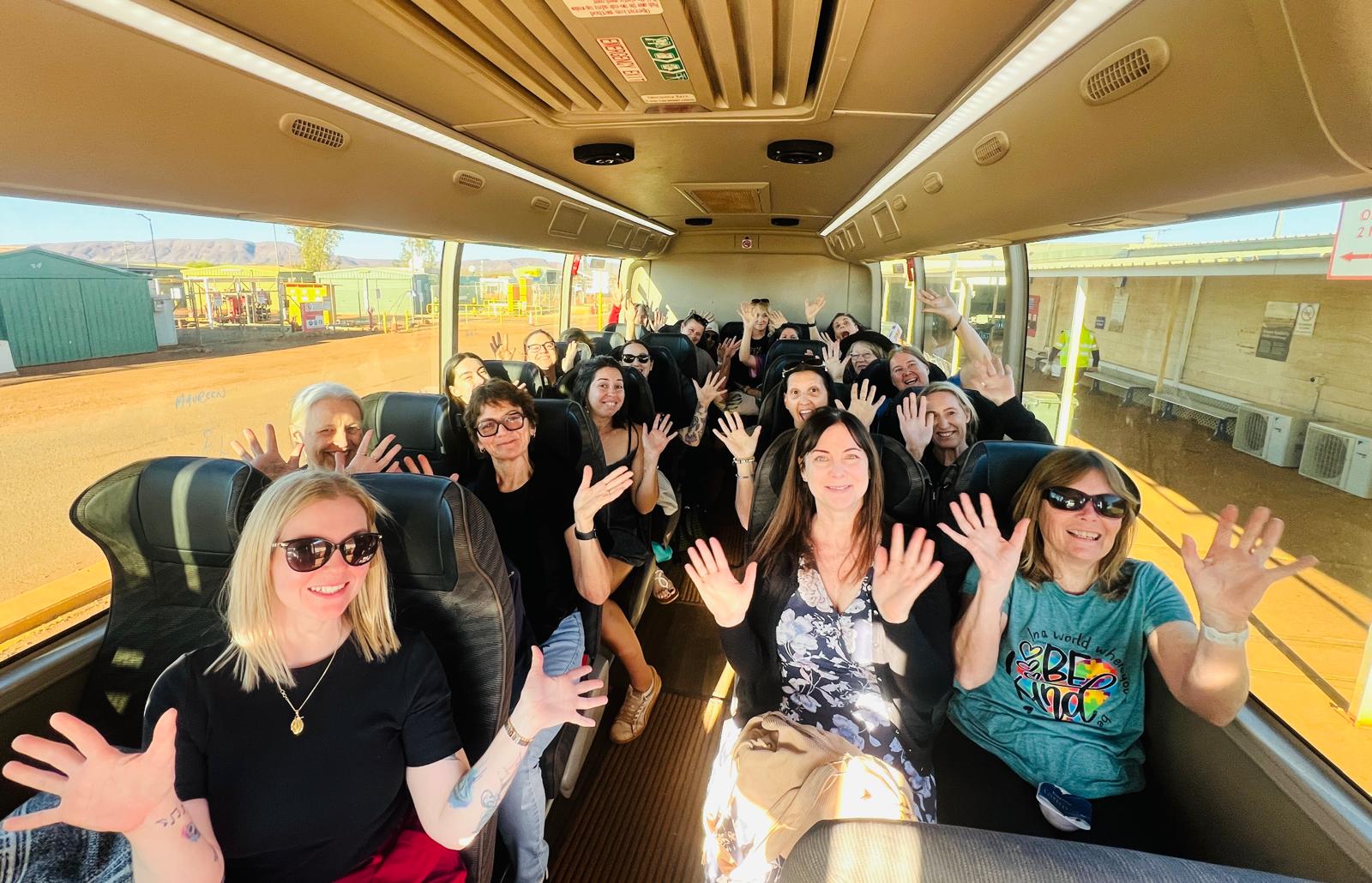 Ladies HQ women smiling and waving from their seats inside the air-conditioned coach